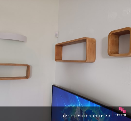 מדפים מעץ מותקנים על קיר לבן